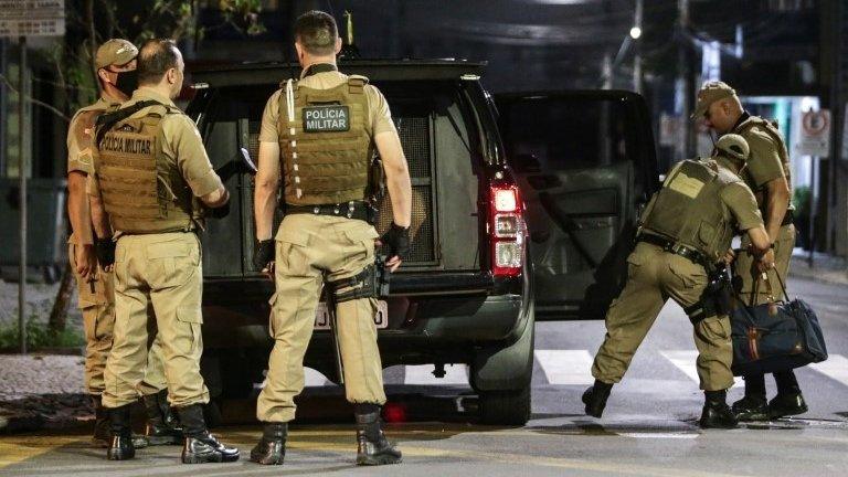 Police collect money left behind by assailants in the aftermath of a bank robbery in Criciuma, Brazil, 01 December 2020.