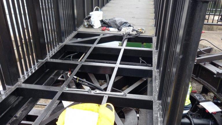 A close up of the bridge deck, which has black large squares as part of the bridge deck has been removed.