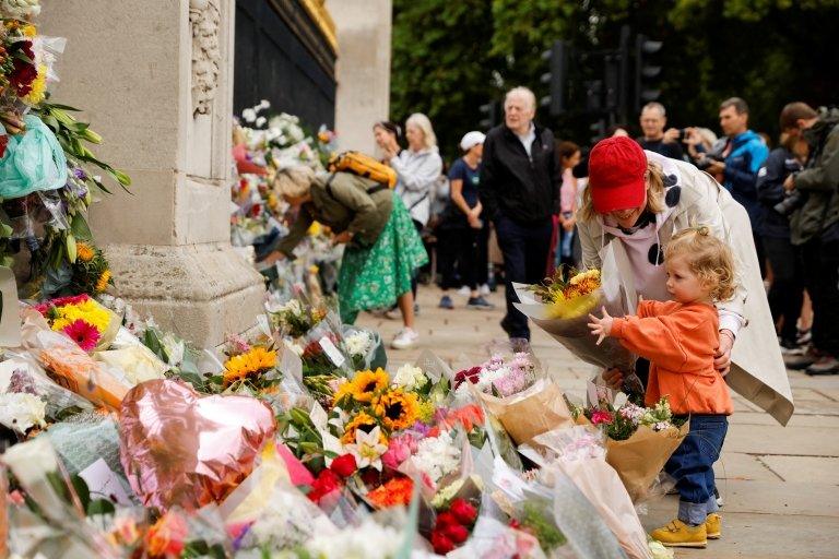 Bertie and mum Stacey lay a bouquet in front of Buckingham Palace