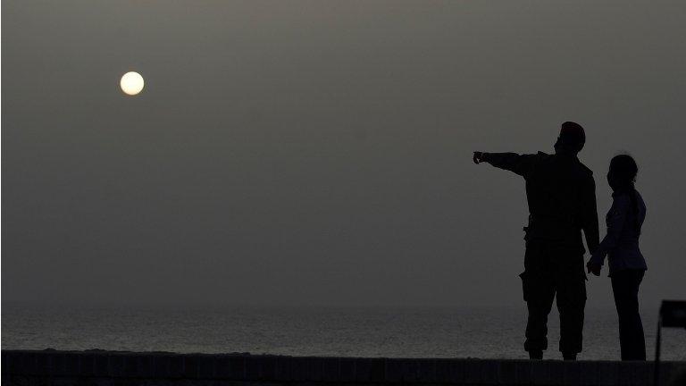 A couple look at the sea as a vast cloud of Sahara dust is blanketing the city of Havana on June 24, 2020.