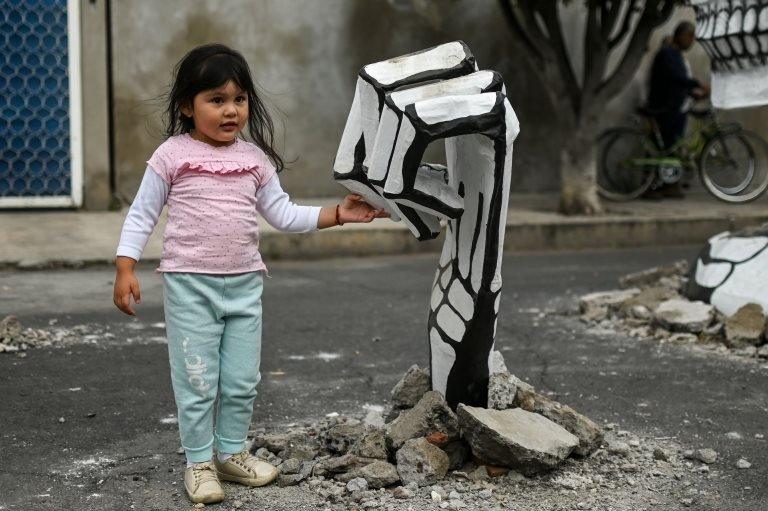 A girl touches the "hand" of a cardboard skeleton