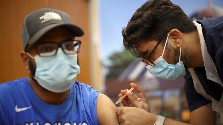 A man receives an injection with a dose of AstraZeneca coronavirus vaccine, at a vaccination centre in Baitul Futuh Mosque