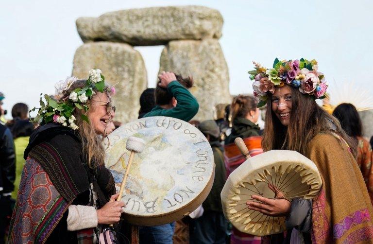 laughing women at Stonehenge playing drums