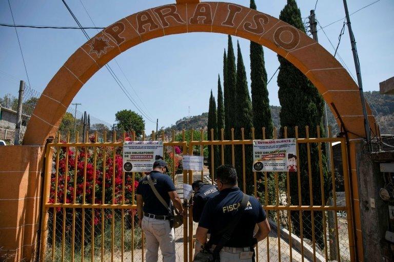 An agent places a lock and chain on a gate at a clandestine cockfighting ring following the killing of at least 20 people on Sunday night during an attack, authorities said, in Zinapecuaro, Mexico March 28, 2022