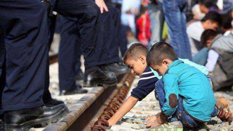 Migrant children play at the feet of Croatian police at a railway station on Croatia's border with Serbia - 17 September