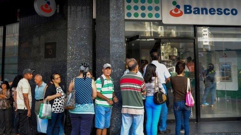 People queue outside a bank in Caracas in an attempt to deposit money, on December 13, 2016. Venezuelan President Nicolas Maduro ordered on December 12 the border with Colombia sealed for 72 hours, accusing US-backed "mafias" of conspiring to destabilize his country"s economy by hoarding bank notes