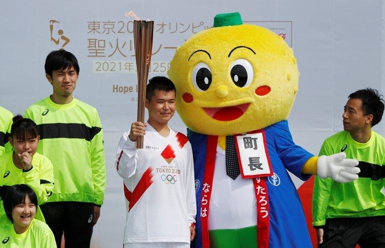 Here a torchbearer poses with Naraha town mascot Yuzutaro after running his leg of the Tokyo 2020 Olympic torch relay.