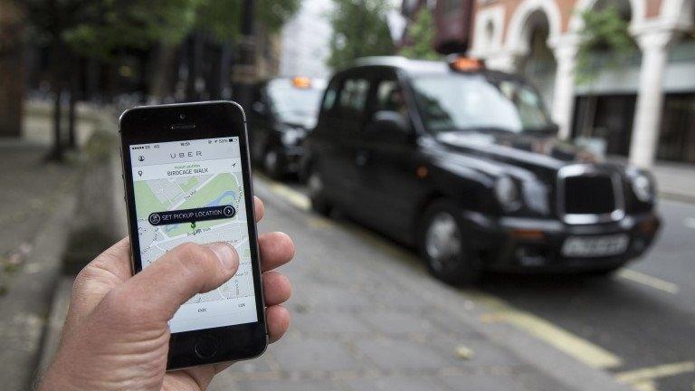 A smartphone displays the "Uber" mobile application which allows users to hail private-hire cars from any location