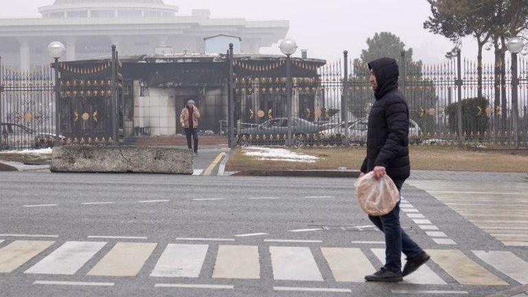 A man walks in front of a the burned out presidential building in Almaty