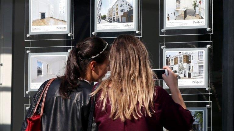 girls looking in estate agent window