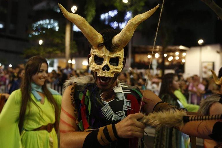 An artist wearing horn and pointing an arrow parades through Medellín