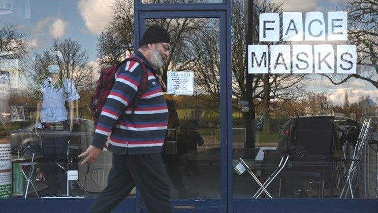 A man walks past a store selling face masks