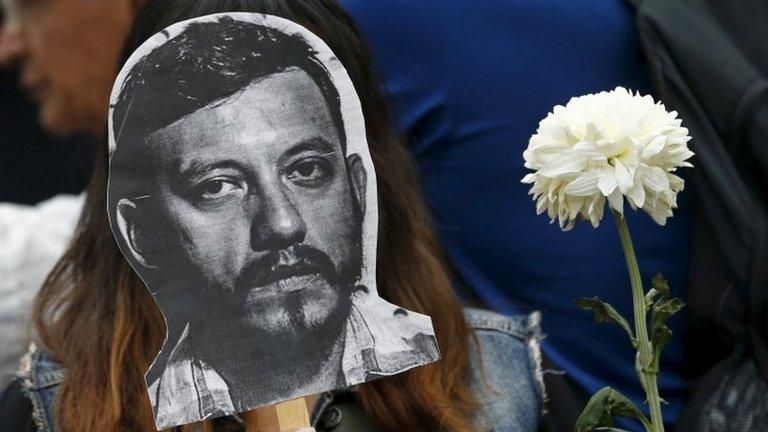 An activist holds up a picture of photojournalist Ruben Espinosa during a protest against his murder at the Angel of Independence monument in Mexico City on 2 August, 2015