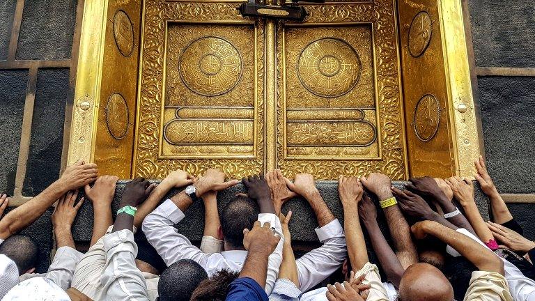 Muslim pilgrims touch the golden door of the Kaaba, Islam"s holiest shrine at the Masjidil Haram, Islam"s holiest site