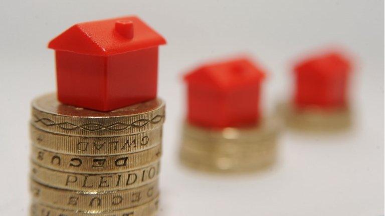 Monopoly house sitting on top of pound coins