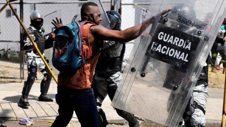 A migrant scuffles with a police officer in riot gear during a protest to demand speedy processing of humanitarian visas to continue on his way to the United States, outside the office of the National Migration Institute (INM) in Tapachula, Mexico February 22, 2022.