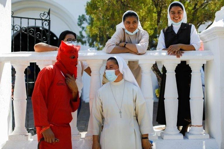 A man dressed as a demon talks to a nun as he participates in a ceremony known as Los Talciguines, as part of religious activities to mark the start of the Holy Week in Texistepeque, El Salvador, April 11, 2022.