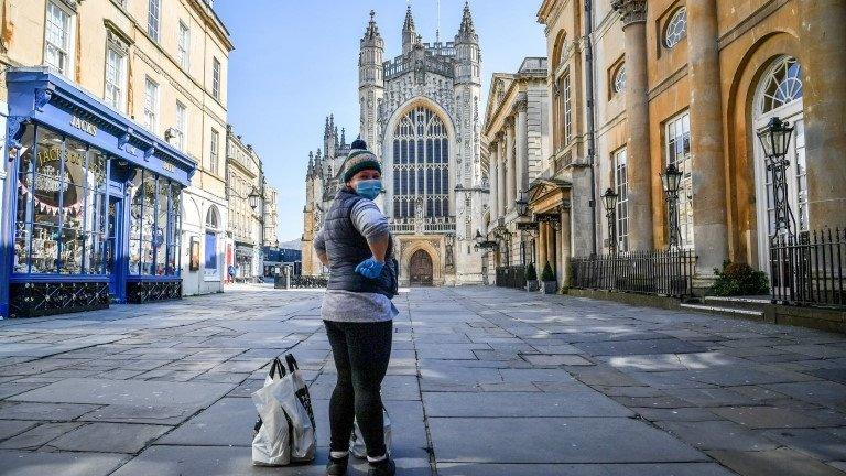 Woman in face mask stood in front of Bath Abbey