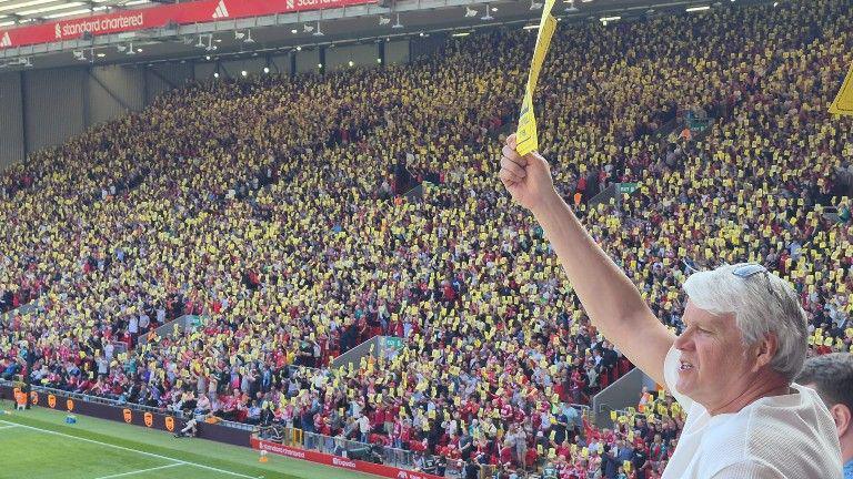 Liverpool fans protest at rising ticket prices by holding up yellow cards