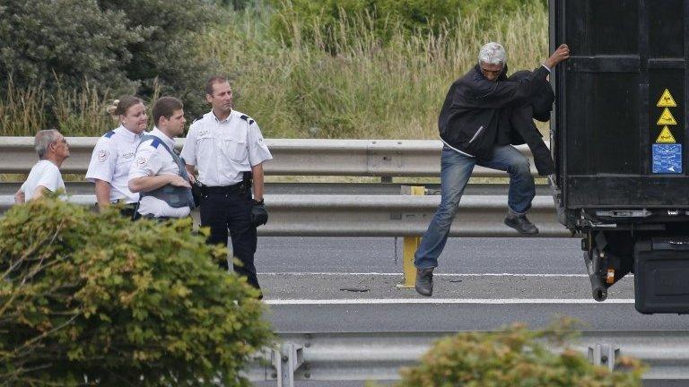 A migrant climbing down from a lorry in Calais