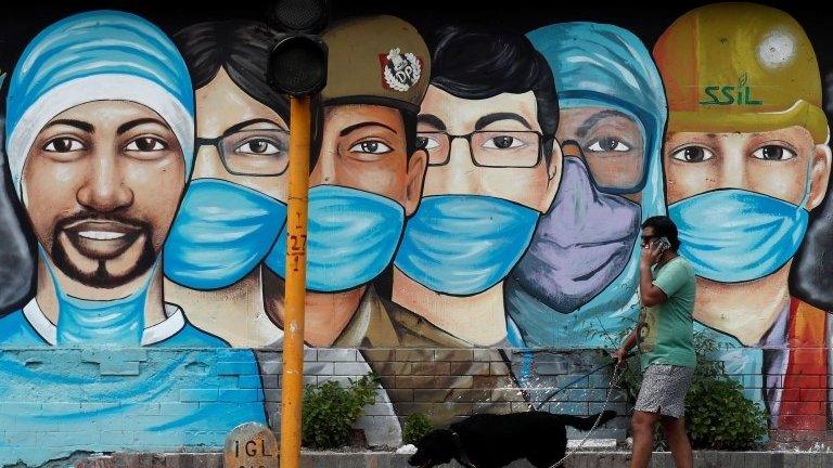 A man walks his dog past a graffiti on a road, amidst the spread of the coronavirus disease (COVID-19), in New Delhi, India, July 17, 2020