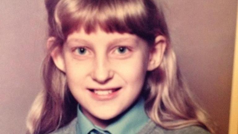 A school photograph of Tracy Borman wearing a school uniform. She has a light blue shirt with a grey jumper over it and has long, blonde hair