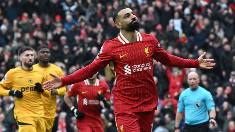 Liverpool's Mohamed Salah holding his arms out in celebration