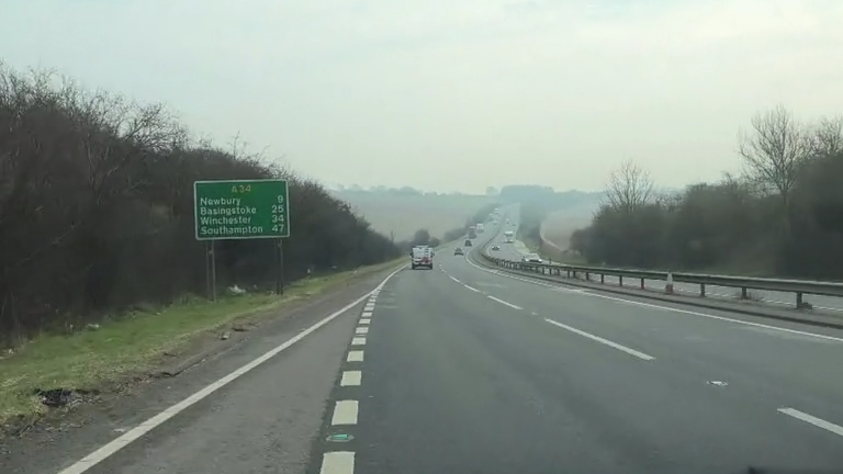 A passenger's point of view, driving onto the A34 from the slip road. The dual carriageway stretches off into the distance among scenic green fields and up a hill.