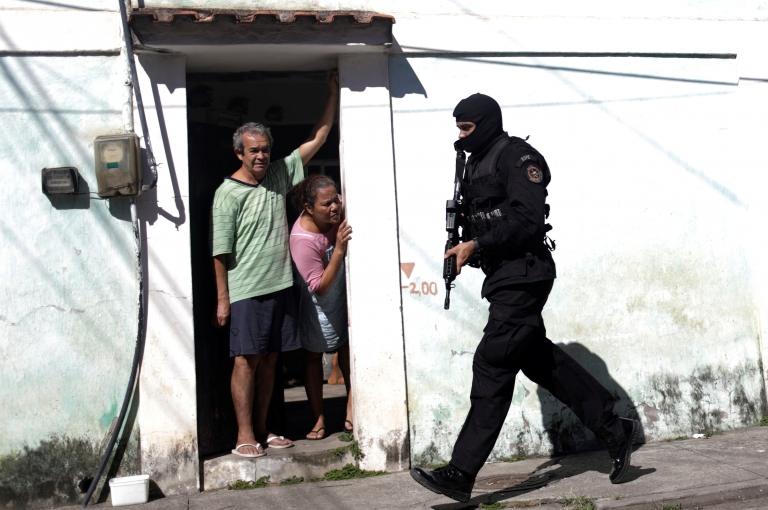 Residents look on as policemen patrol during an operation against drug dealers in Cidade de Deus slum in Rio de Janeiro, Brazil, July 10, 2017