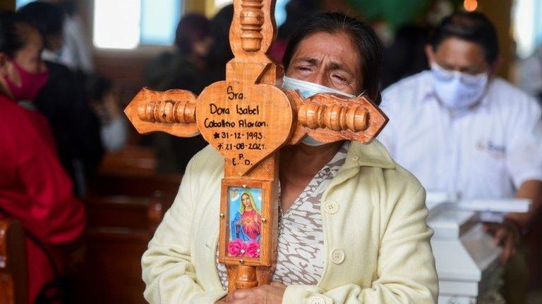 A woman carries a cross for a woman who was killed along with others in a mudslide after Hurricane Grace pummeled Mexico with torrential rain on Saturday, during a funeral ceremony, in Xalapa, Mexico August 22, 2021.