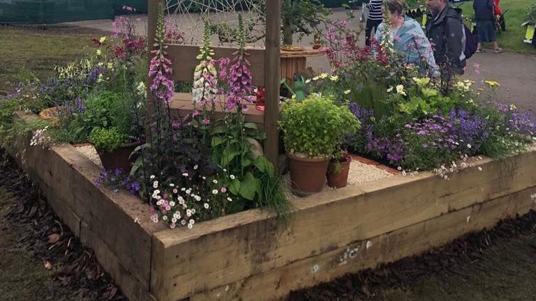 Wooden bordered-garden with flowers in pots and beds