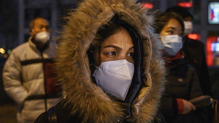 Chinese office workers wear protective masks as they line up for the bus after leaving work on March 2, 2020 in Beijing, China