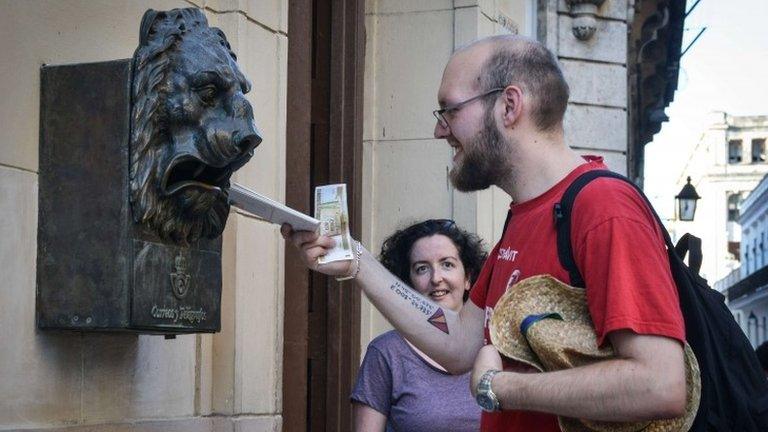 Tourists drops letter in a letter box in Havana