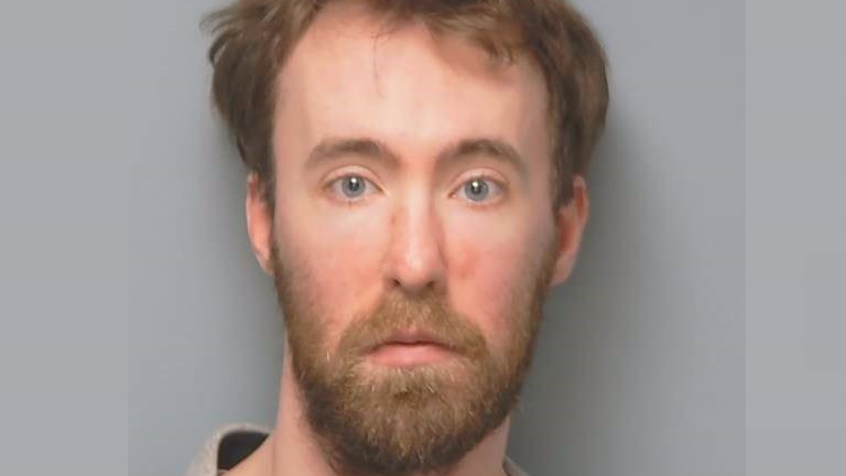 A police custody photo of Joshua Powell, who has light-brown hair and a full beard.