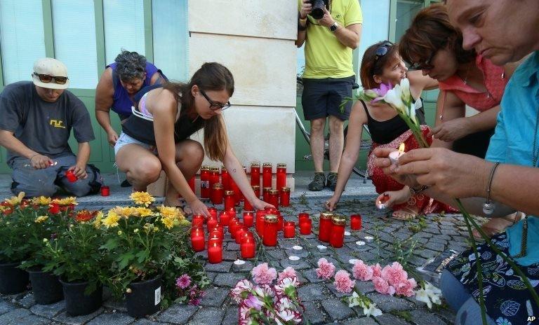 People light candles in front of the police station in Eisenstadt, Austria, Thursday, Aug 27, 2015.