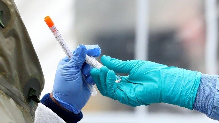 Medical professionals pass each other a coronavirus test at a drive-thru testing site at Cambridge Health Alliance Somerville Hospital on April 28, 2020 in Somerville, Massachusetts.