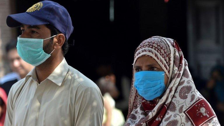 Residents wear protective facemasks as a prevention measure against the Covid-19 coronavirus on a street in Multan in Pakistan