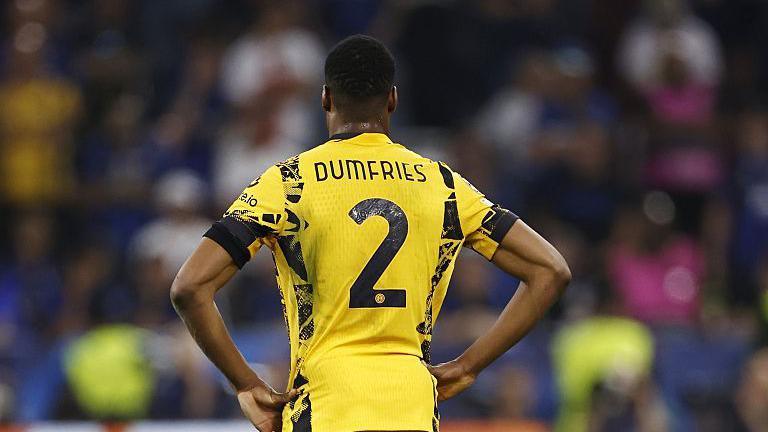 A rear view of Denzel Dumfries in a yellow Inter Milan strip with his name on it and the number two