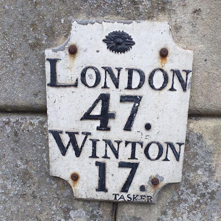 A metal plaque mile marker showing the distance to London and Winton