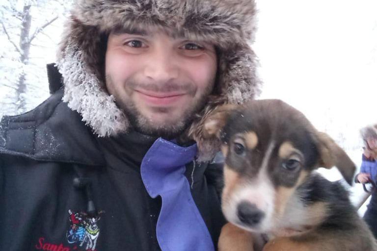 Bernard Mongan posing for a photo with a dog. Mr Mongan is wearing a fluffy hat.