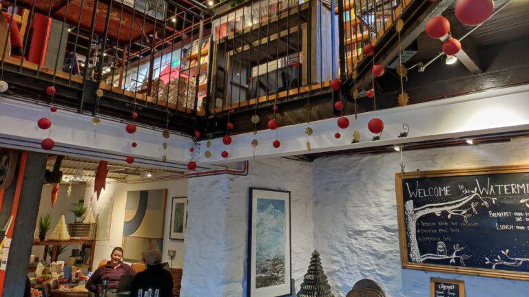 A busy café is pictured with two floor and decorated with pictures and Christmas bunting. 