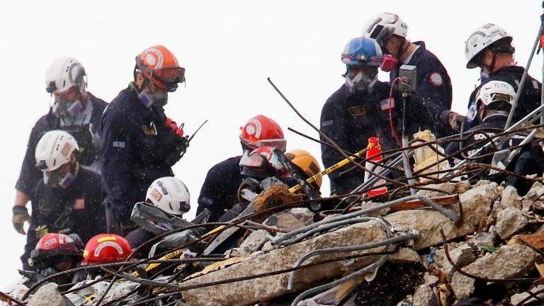 Emergency workers conduct search and rescue efforts at the site of a partially collapsed residential building in Surfside