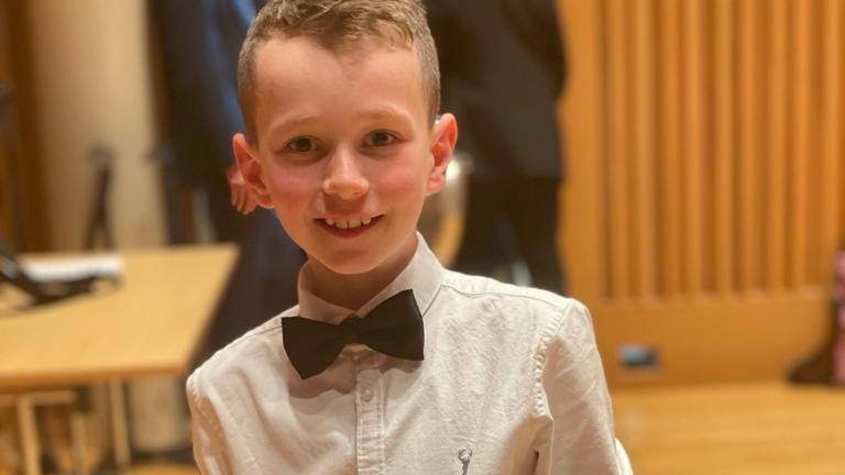 A young boy wearing a white t-shirt and black bow tie