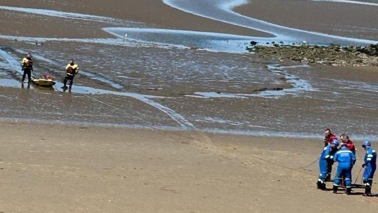 Wirral Coastguard Rescue Team on beach rescuing woman from sand