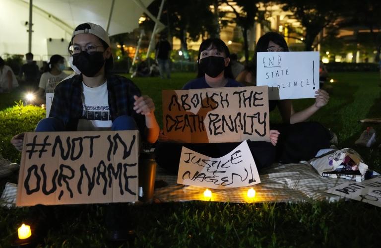 People hold candles and placards during a candlelight vigil against the death penalty for Malaysian national Nagaenthran K. Dharmalingam