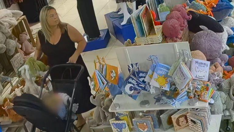 CCTV imagery of a blonde woman pushing a pram and holding a Jellycat plush toy in a shop surrounded by shelves with Jellycat teddies on 