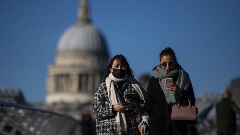 Woman wearing a mask walking on a bridge over the Thames