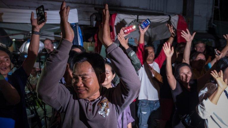 Onlookers at the junction in front of Chiangrai Prachanukroh Hospital watch and cheer as ambulances transport the last rescued schoolboys and their coach from a helipad nearby