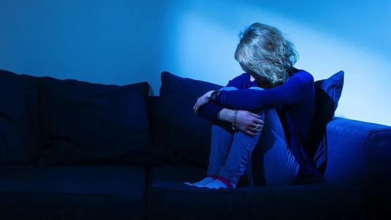 A young person on a sofa curled up