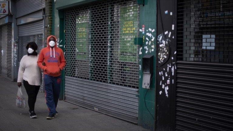 Couple walking past boarded up shop